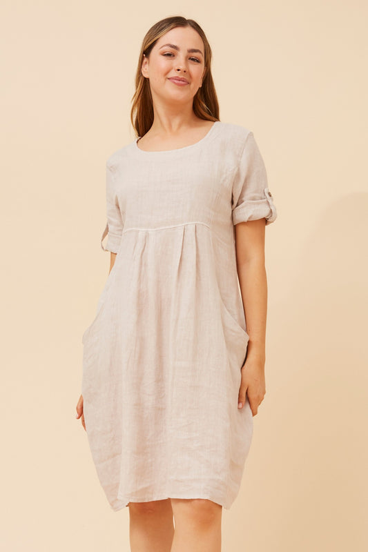 Pisa Linen Short Dress in LINEN – airy linen texture, unlined breathable feel, relaxed knee-length fit with roll-up sleeves. Front 3-quarter view.